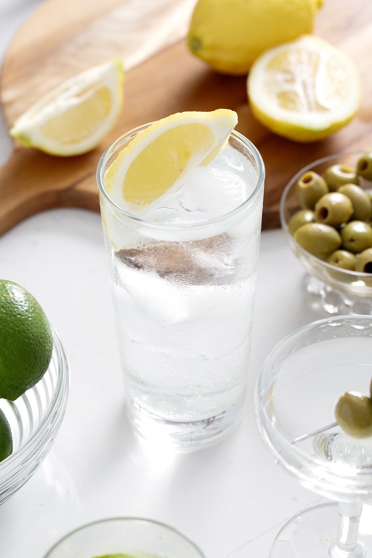 Tom Collins garnishes with a lemon wedge surrounded by lemons and olives