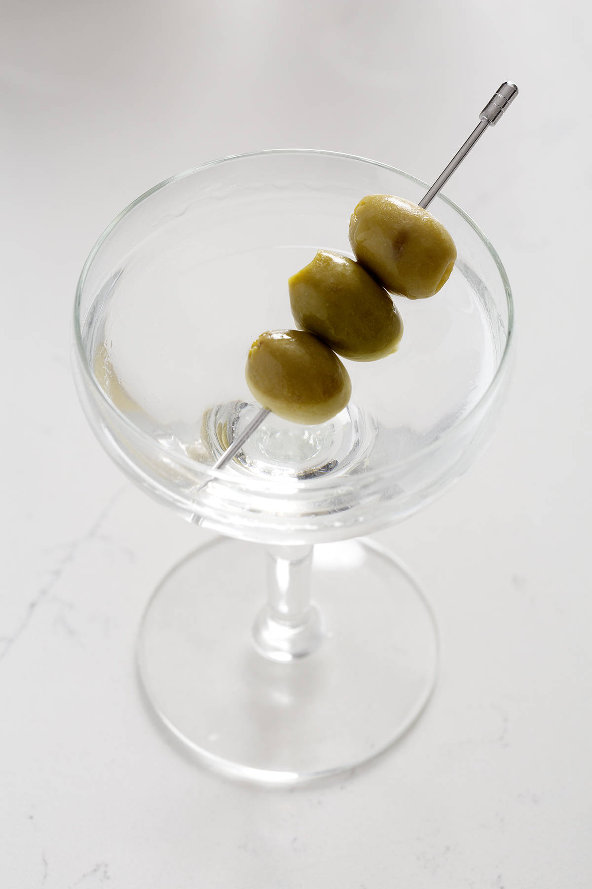 couple glass with dry gin martini with olives on white counter