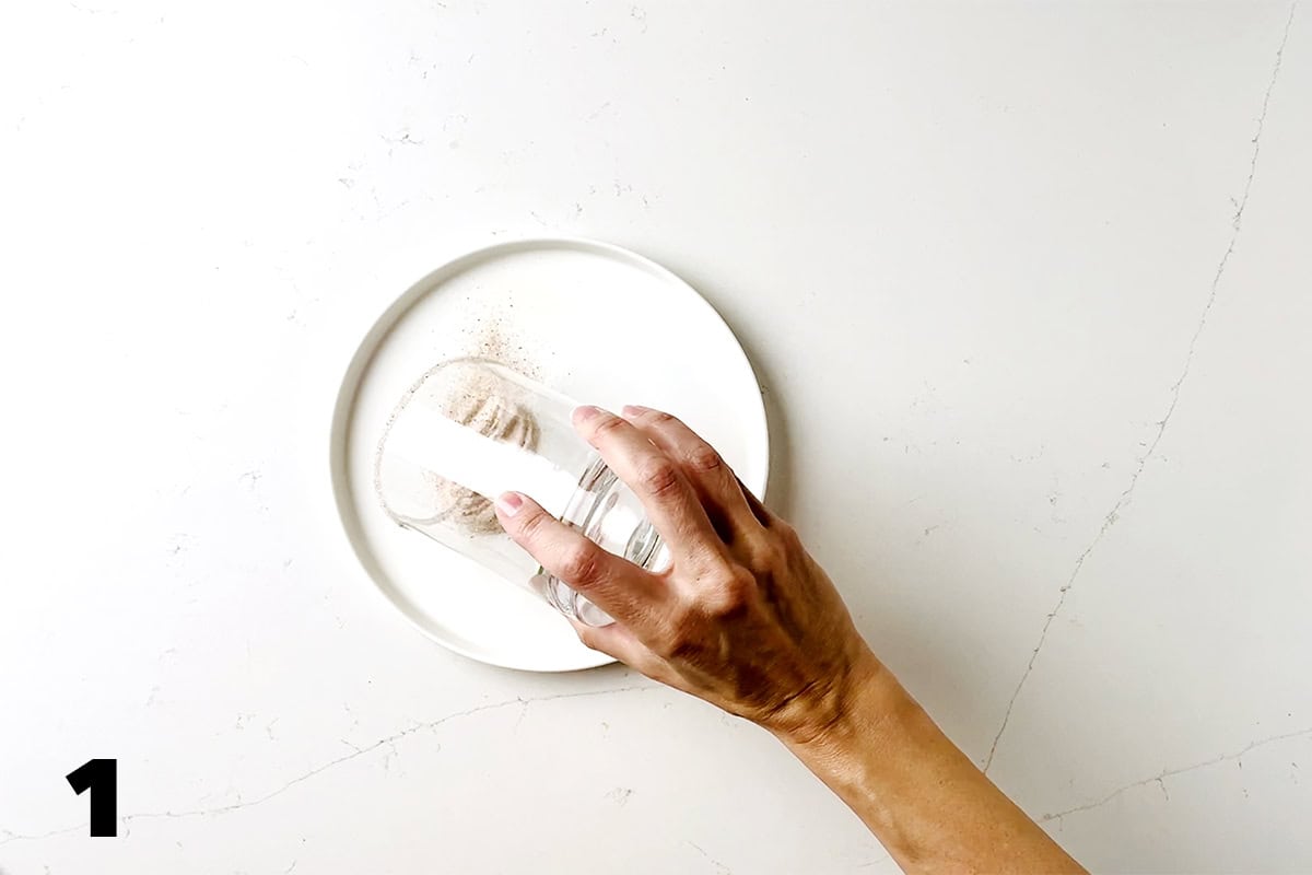 hand holding glass dipping it into salt on plate