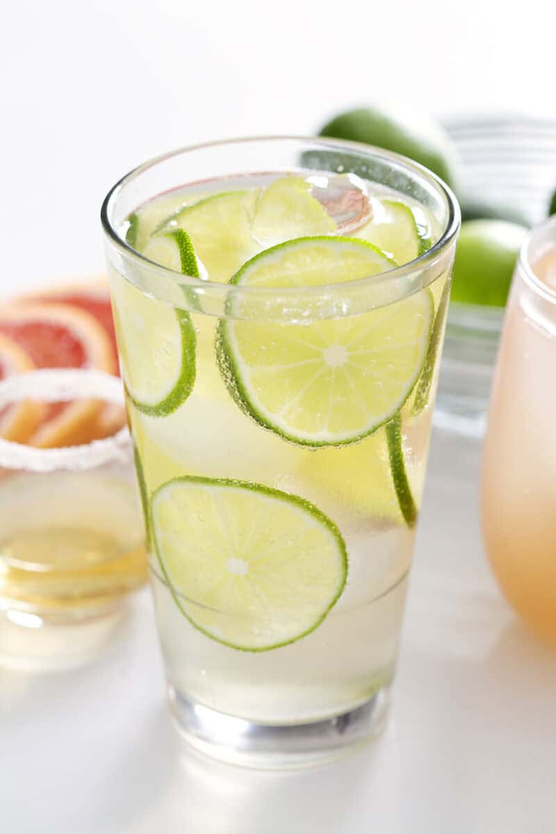 highball glass filled with tequila and soda garnished with lime wheels