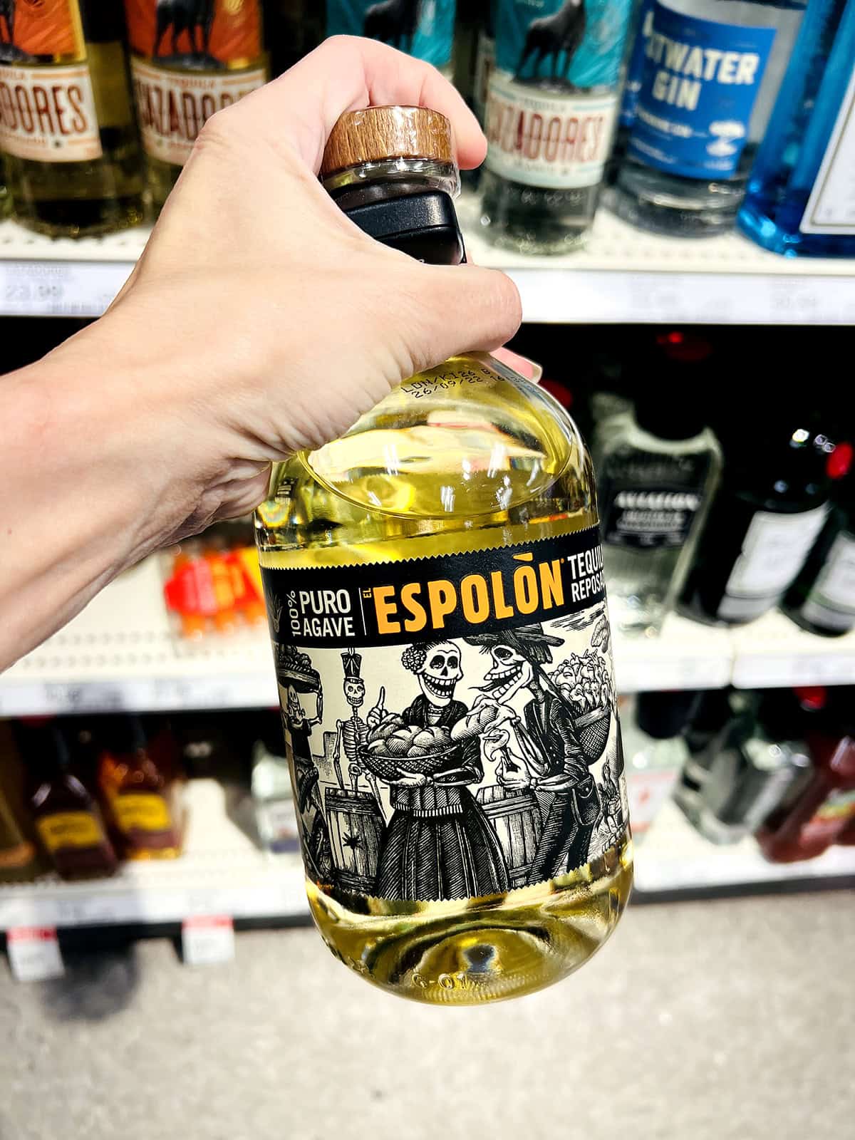 hand holding espolon tequila bottle in grocery store aisle
