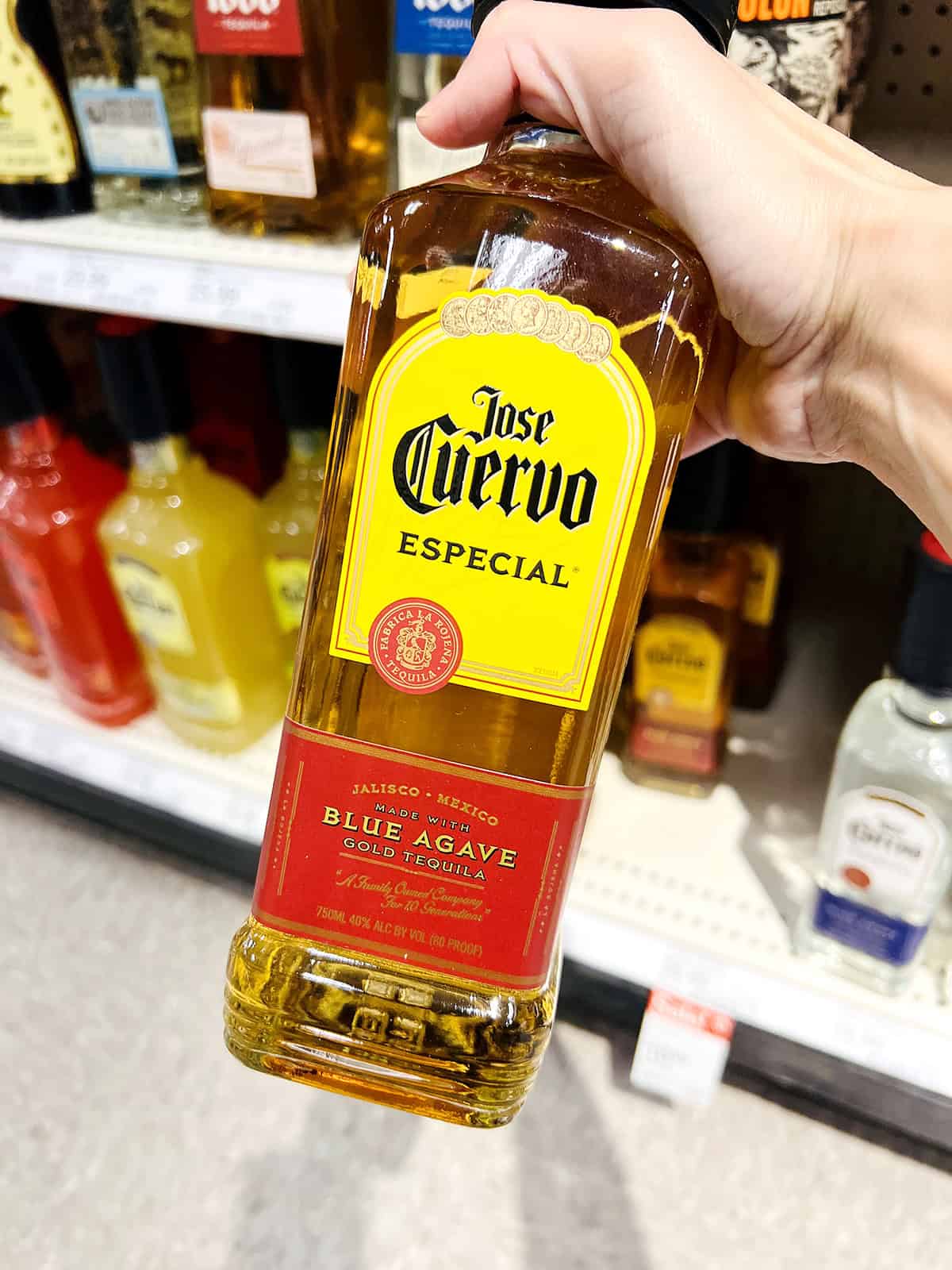hand holding jose cuervo tequila bottle in grocery store aisle