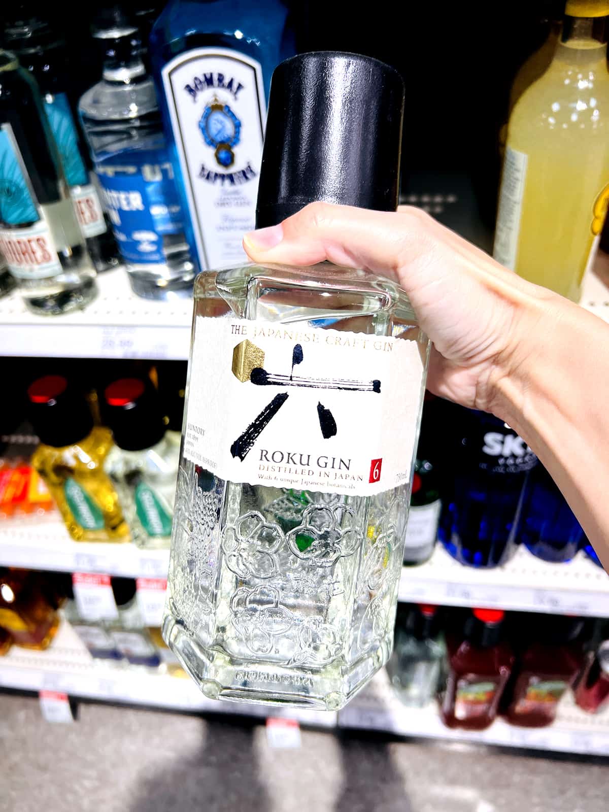 hand holding bottle of roku gin in grocery store aisle