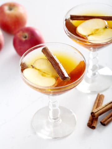 apple cider mocktail with apples and cinnamon sticks